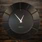 Black HDMR wall clock displayed in modern interior